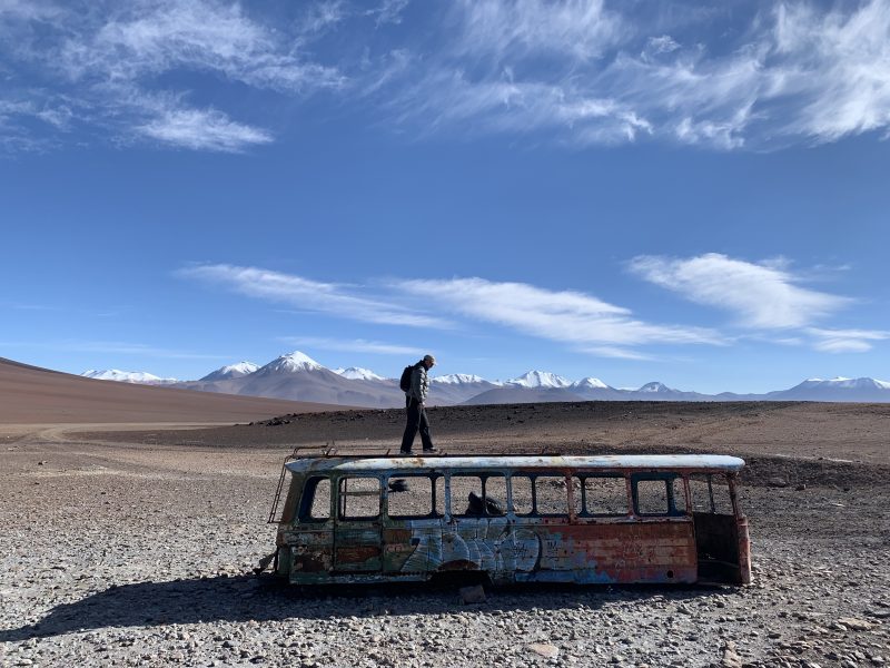 4WD tour from San Pedro de Atacama to Uyuni - Burnt out bus overlooking the Andes mountains and volcanoes on the Altiplano