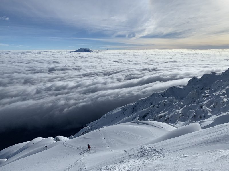 Climbing Cotopaxi Volcano - early morning view above the clouds and down the snow slopes