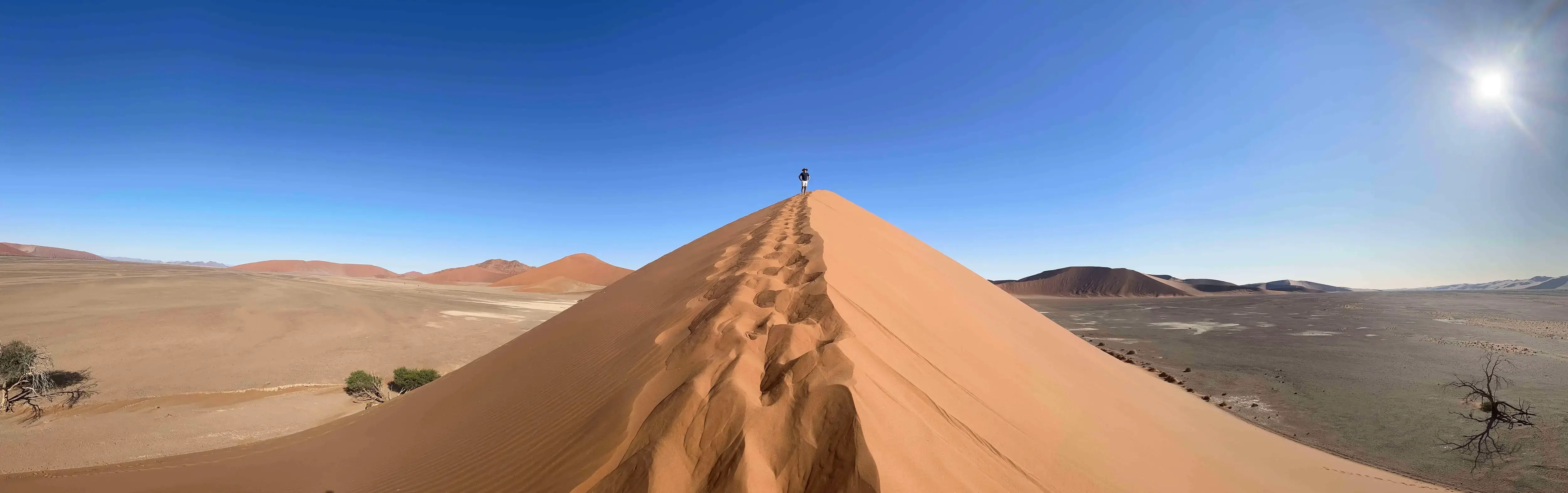 Climbing the red desert dunes of Namibia's Sossusvlei with Mars-like landscape